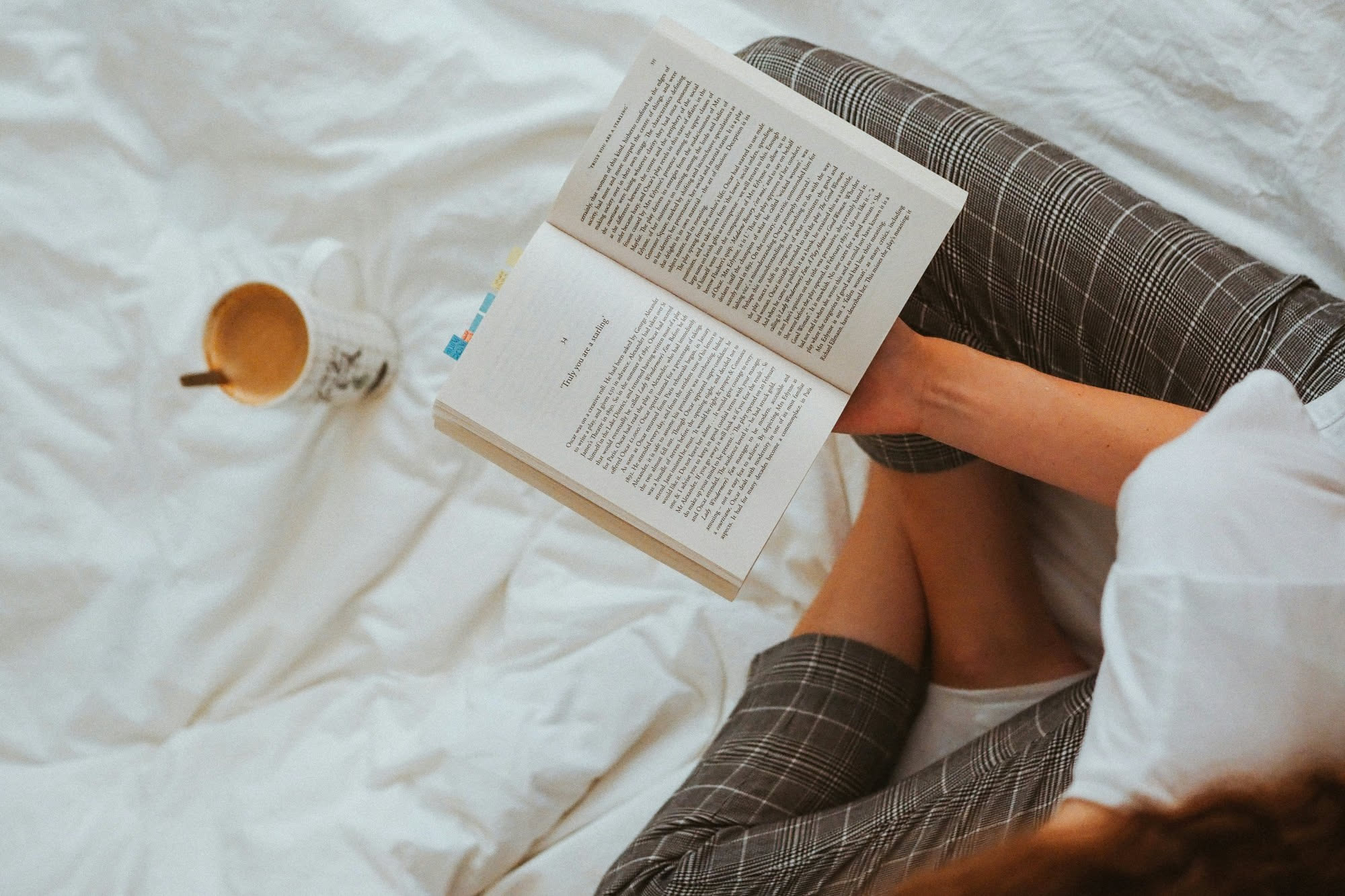 Persona che sfoglia un libro davanti a uno scaffale di libreria