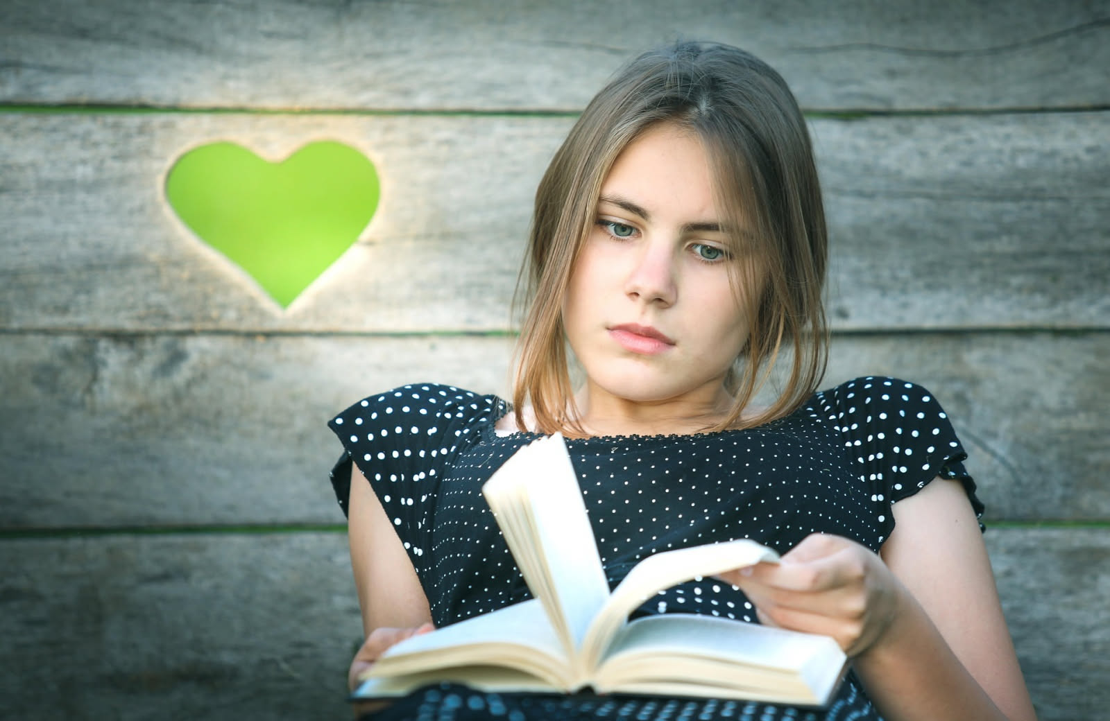 Camera con letto e comodino carico di libri accanto a una finestra