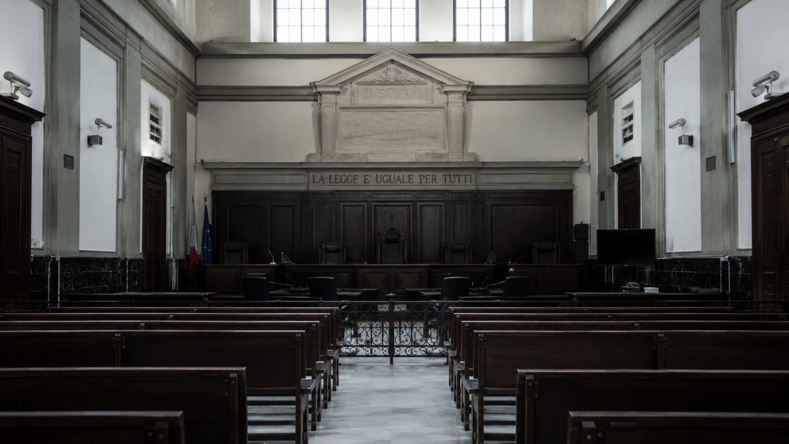 Aula vuota con banchi di legno scuro e luce fredda dalle finestre alte